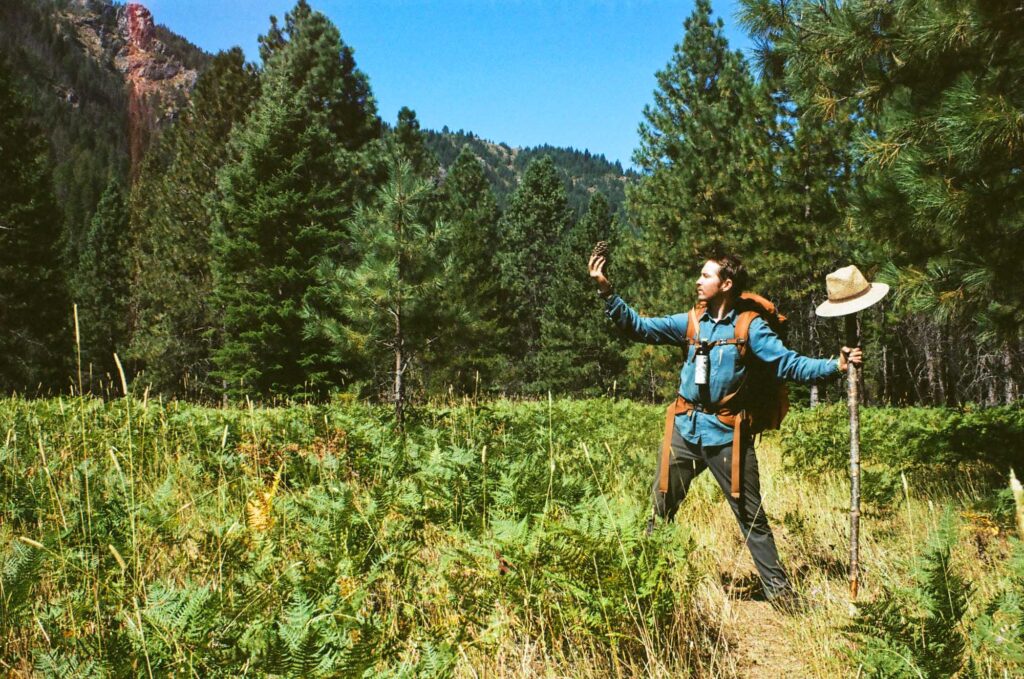 Man in field holding pinecone.